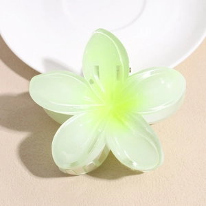 Close-up of translucent green resin plumeria claw clip with sturdy metal spring mechanism