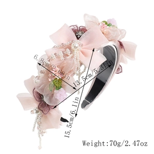 Détail d'un serre-tête rose avec fleurs en tissu, perles, pompons et dimensions