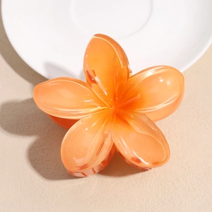Detailed view of an orange frangipani flower hair claw made of polished resin material