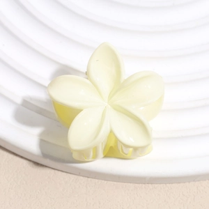 Gros plan d'une pince à cheveux fleur jaune pâle avec finition mate sur plaque texturée