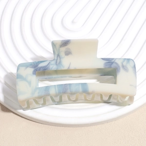 Detailed view of large square claw clip with blue floral pattern on creamy white acetate