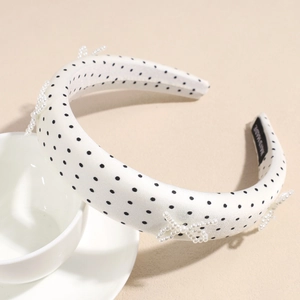 Detailed shot of white satin polka dot headband with elegant pearl bow embellishments