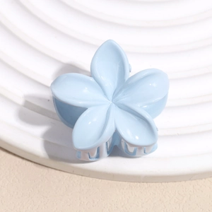 Détail d'une pince à cheveux fleur bleue claire sur un support d'exposition blanc