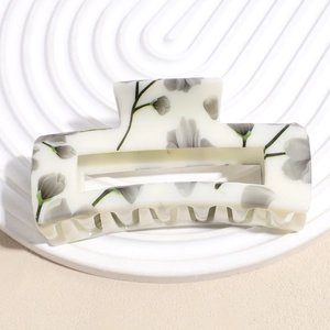 Macro shot of large rectangular hollow hair claw clip with cream floral pattern