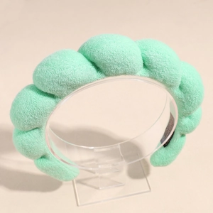 Détail du serre-tête éponge vert menthe avec texture nuageuse ondulée sur support