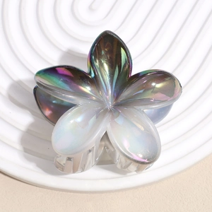 Macro shot of iridescent plumeria hair claw clip with a pearlescent finish on a white tray