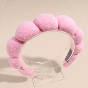 Vue détaillée de la texture du serre-tête en éponge rose sur support acrylique