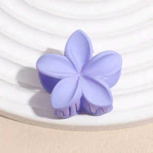Gros plan d'une pince à cheveux fleur mauve mate sur un socle rond ondulé