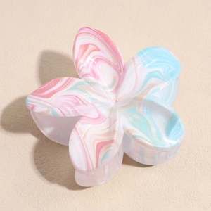 Dettaglio di una grande molletta per capelli a fiore marmorizzato con sfumature blu e rosa