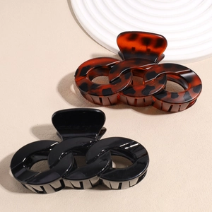 Large tortoiseshell and black chain hair clips for thick hair on a minimal stone display