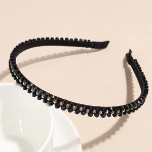 Detailed view of black crystal double-row headband with sparkling rhinestones on white bowl