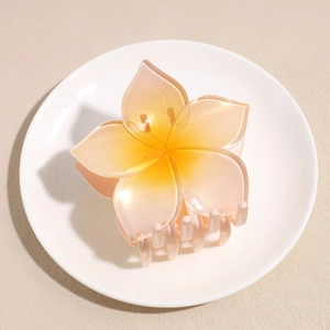 Macro detail of a translucent five-petal flower hair claw with orange-pink gradient glitter