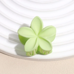 Vue détaillée d'une pince à cheveux fleur vert clair mat sur un plateau blanc décoratif