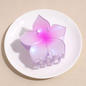 Macro detail of pearlescent purple plumeria flower hair claw clip with gradient effect