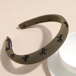 Detail view of khaki sponge headband with black bow patterns and hand made label