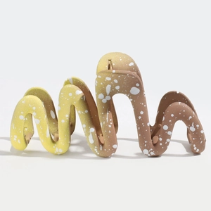 Detail of matte gradient hair claw clip with wave shape and yellow to brown splash pattern