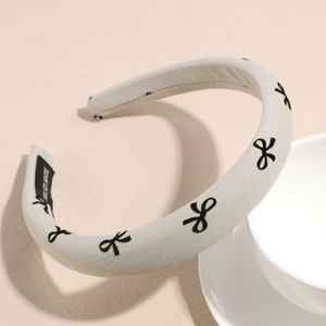 Close-up of handmade grey sponge headband with black bow patterns and hand made label