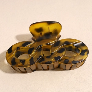 Macro view of leopard print hair claw clip with chain link design on beige background