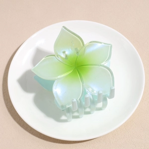 Macro detail of gradient green pearl flower claw clip on minimalist white display dish