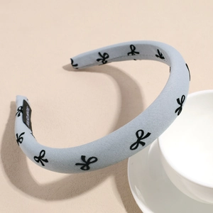 Detail of light blue padded headband with bow pattern and handmade label on the inner side