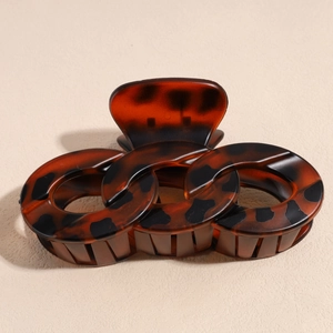 Detail view of large amber tortoiseshell hair claw clip with unique interlocking ring design