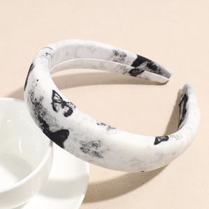 Close-up of wide padded sponge headband featuring black and white ink butterfly pattern