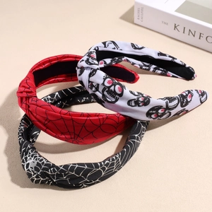 Three Halloween knotted headbands with spider web and skull patterns on beige background