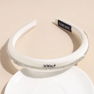 Détail du serre-tête en satin blanc avec strass et étiquette de fabrication artisanale
