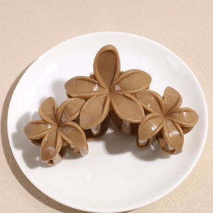Détail de trois pinces à cheveux fleurs marron brillant sur une assiette en céramique