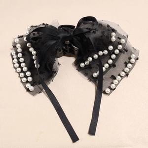 Détail de la pince à cheveux avec nœud en dentelle noire et perles blanches chic