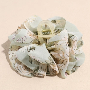 Macro detail of large floral fabric hair claw clip with vintage rose pattern and ruffles