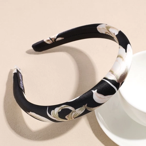 Detailed close-up of handmade satin headband with floral patterns and woven label