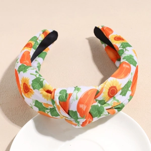 Detail of fabric headband with pumpkin and sunflower print and stylish top knot design