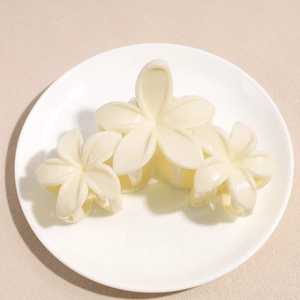 Vue détaillée d'une pince à cheveux à fleurs de couleur crème sur assiette blanche