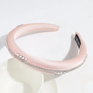Détail d'un serre-tête en satin rose avec strass et étiquette de fabrication artisanale