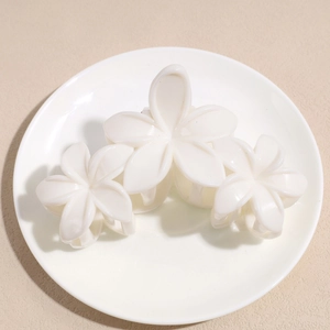 Détail de trois pinces à cheveux fleurs en acrylique blanc sur une assiette en céramique