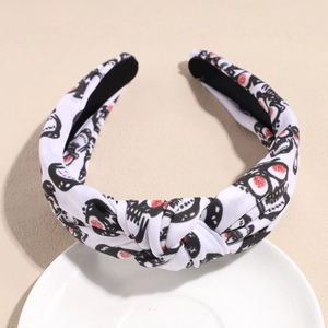 Detail view of white knotted headband with black skull patterns and red eye accents