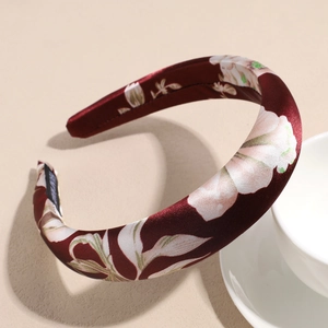 Macro shot of burgundy satin headband with floral patterns and luxury woven label detail