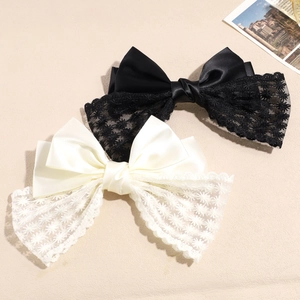 Detail of satin lace bow hair clips in black and beige with star embroidery