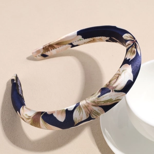 Detailed macro view of navy blue satin floral headband showing the handmade woven label