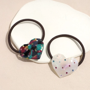 Elegant heart-shaped hair ties set with colorful rhinestones on decorative stone board