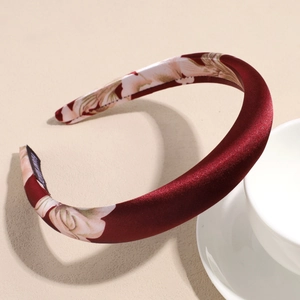 Detail of burgundy satin headband with floral patterns and handmade label inside