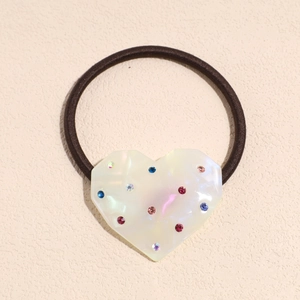 Detailed close-up of heart-shaped resin hair tie with colorful inlaid rhinestones