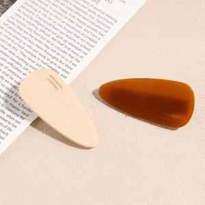 Elegant set of 2 handmade amber and beige teardrop hair clips on decorative background