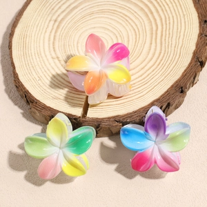 Drei Haarspangen mit Farbverlauf in Blumenform auf einem hölzernen Displayständer