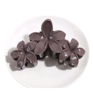 Pince à cheveux élégante marron foncé avec trois fleurs en résine sur plateau blanc