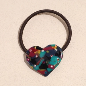 Macro detail of elastic hair tie with colorful rhinestone heart-shaped acetate accessory