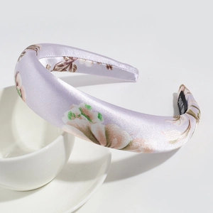 Detail of lavender satin floral headband with Hand Made label on white ceramic cup