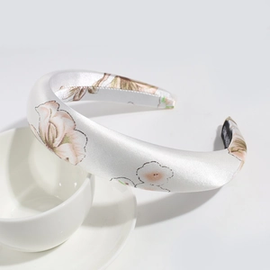 Detailed texture of white satin floral headband with a handmade label on a white cup