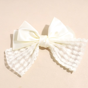 Detail of cream satin bow hair clip with double-layer lace and delicate floral patterns